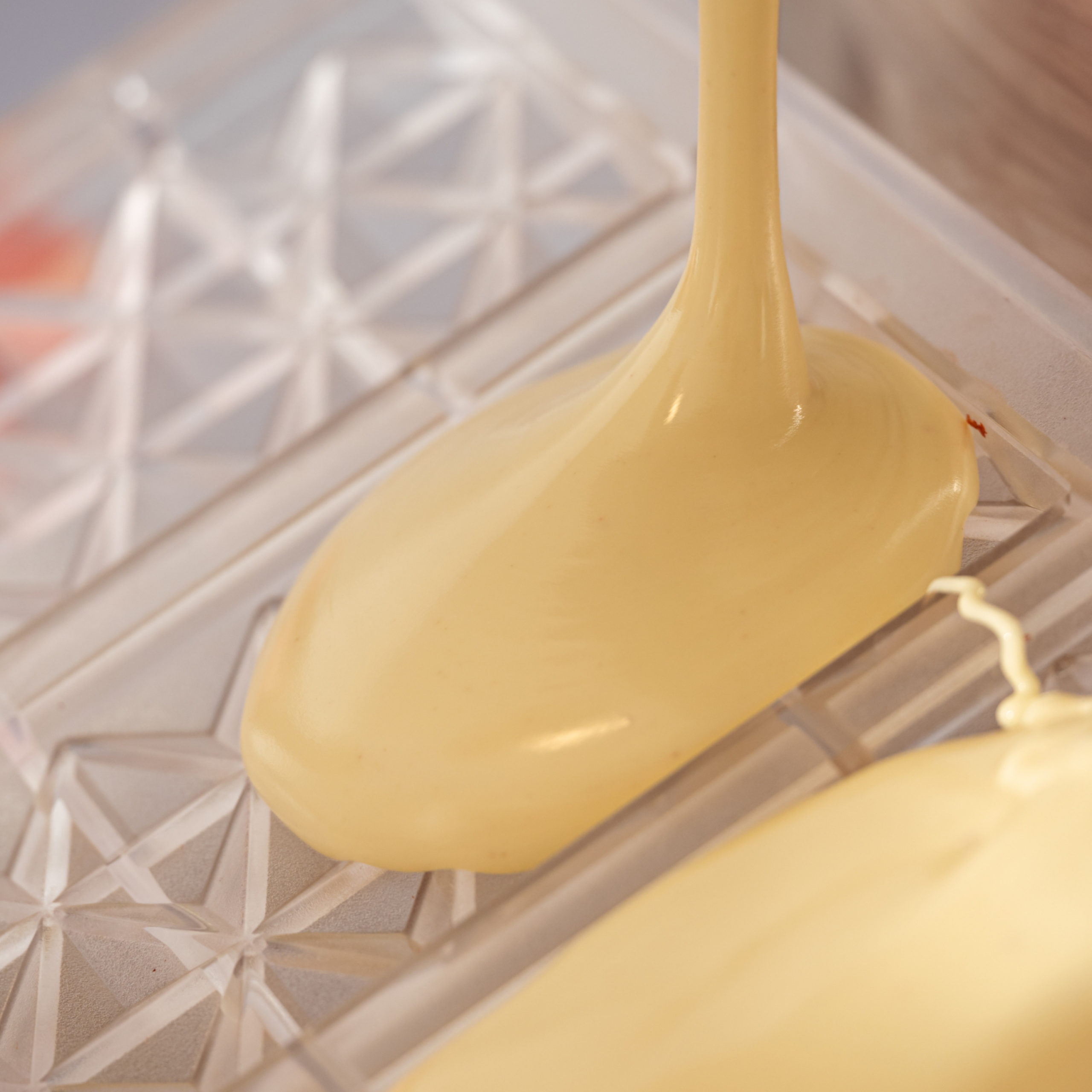 Weisse Schokoladentafeln beim Giessen in die Tafelgussformen in der Bean to Bar Schokoladenmanufaktur Chani Schoggi aus Luzern