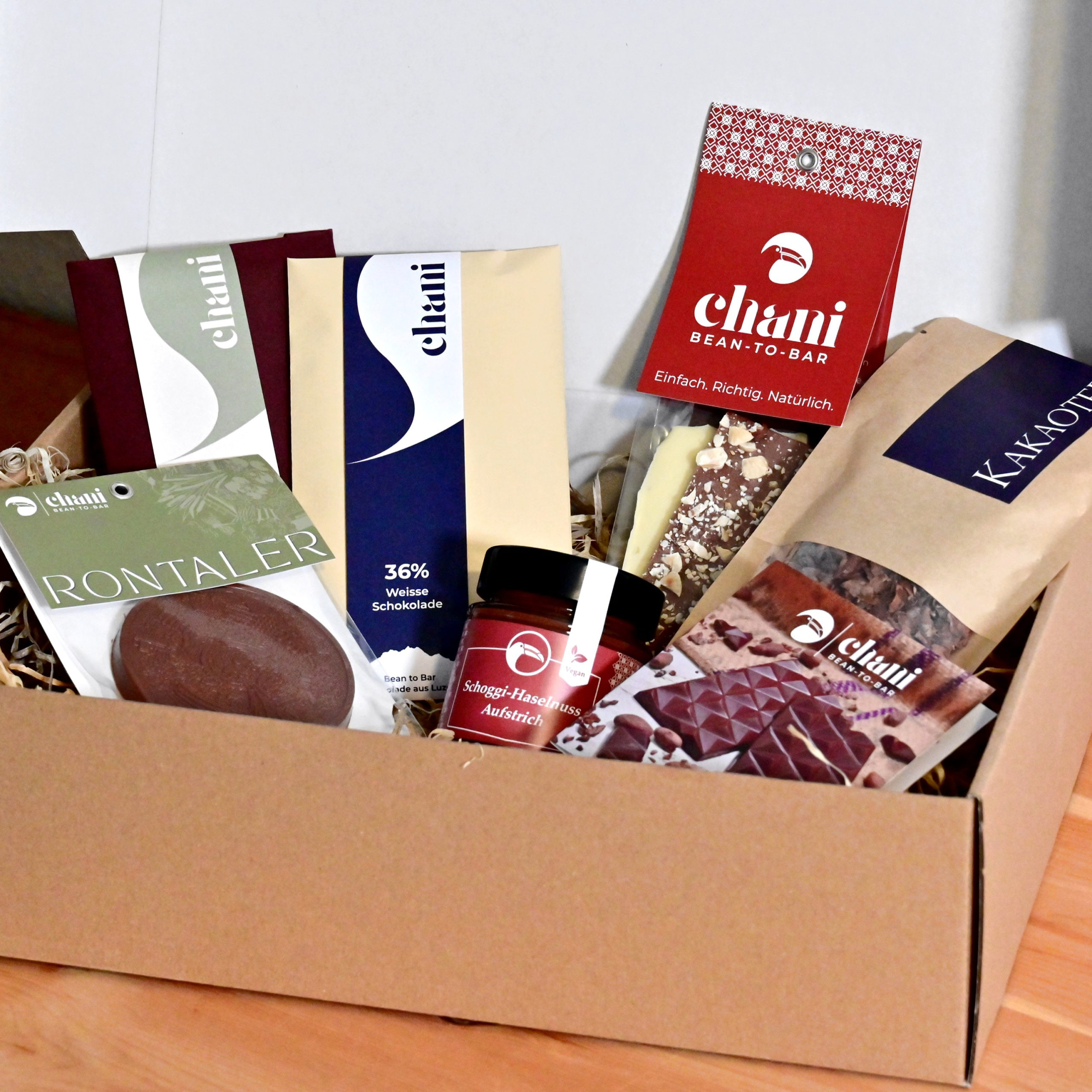 Eine Geschenkbox voller Schoggi-Spezialitäten zum Versenden als feines Schokoladengeschenk. Hergestellt von Chani Schoggi KLG in Ebikon/Luzern.
