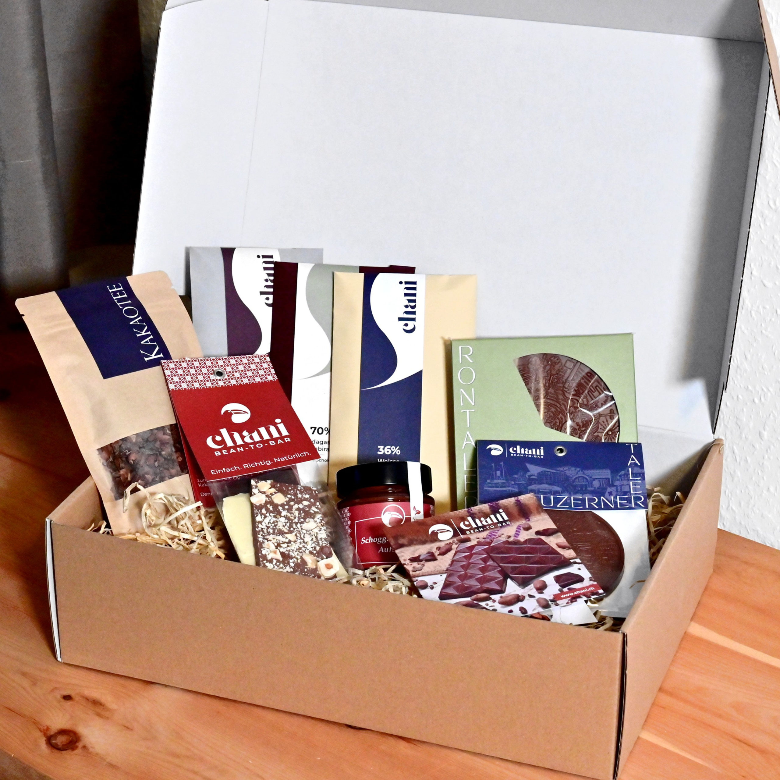 Geschenkbox «Aficionado» | Chani Schoggi Eine Geschenkbox voller Schoggi-Spezialitäten zum Versenden als feines Schokoladengeschenk. Hergestellt von Chani Schoggi KLG in Ebikon/Luzern.