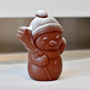 Freddy, der charmante Schoggi-Schneemann aus Milchschokolade – von Hand gegossen und winterlich bestäubt. Ein süsser Genuss für kalte Tage und festliche Momente.